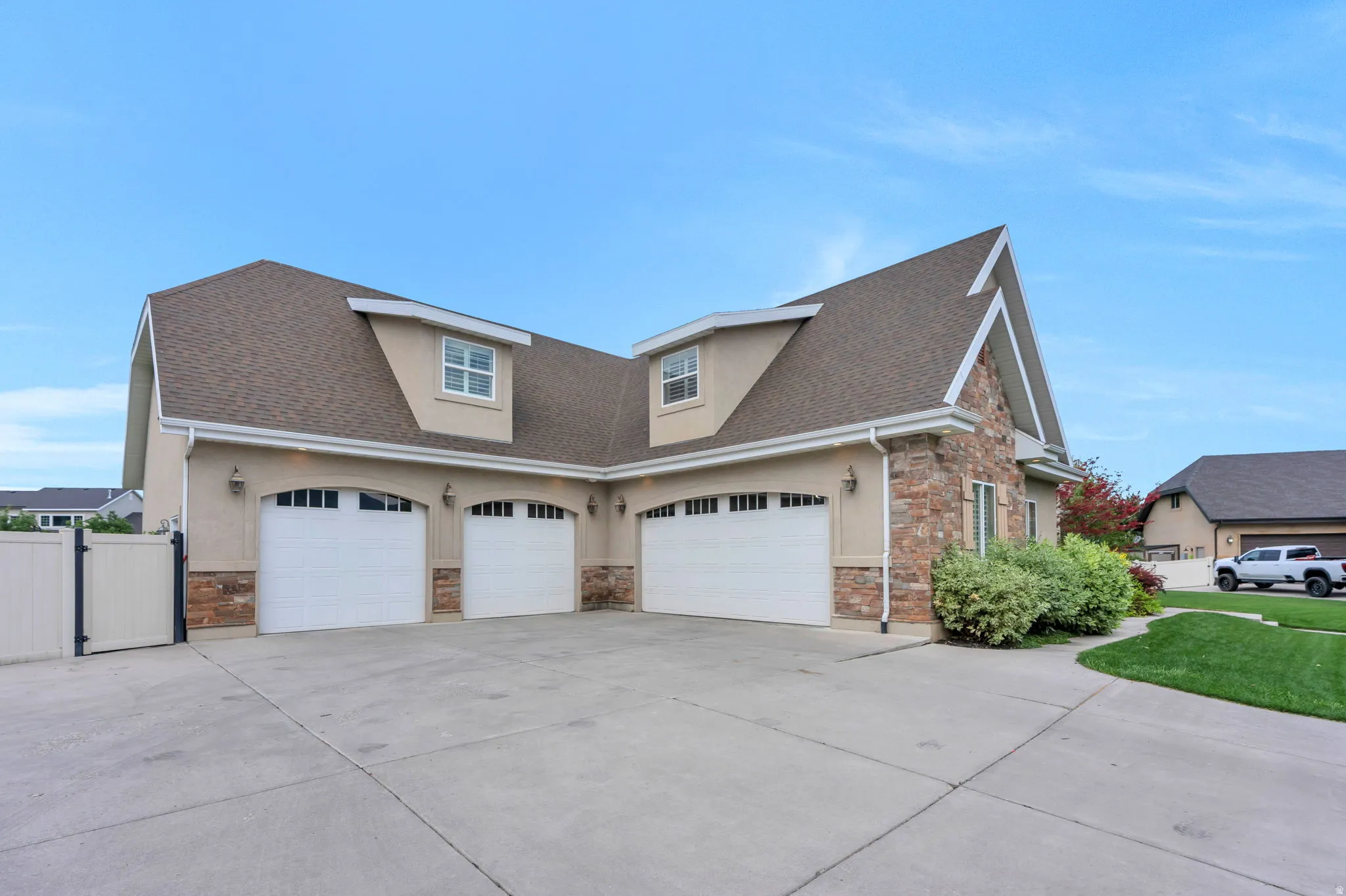 Multi-car garage featuring three arched garage doors, stone veneer accents, and stucco exterior