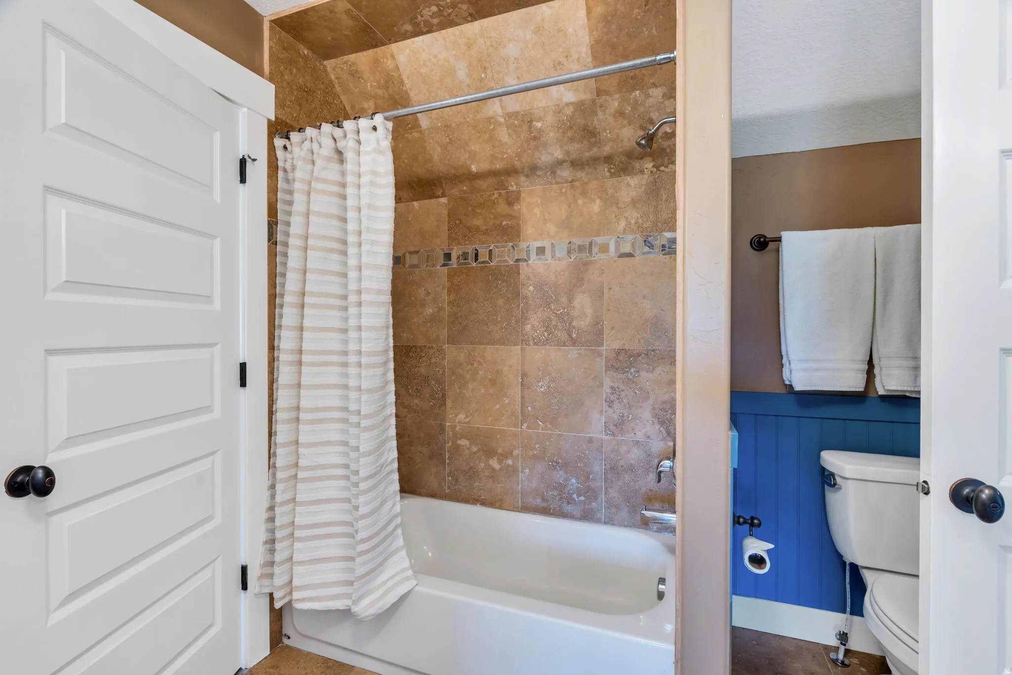 Bathroom featuring toilet and shower / bath combination with curtain
