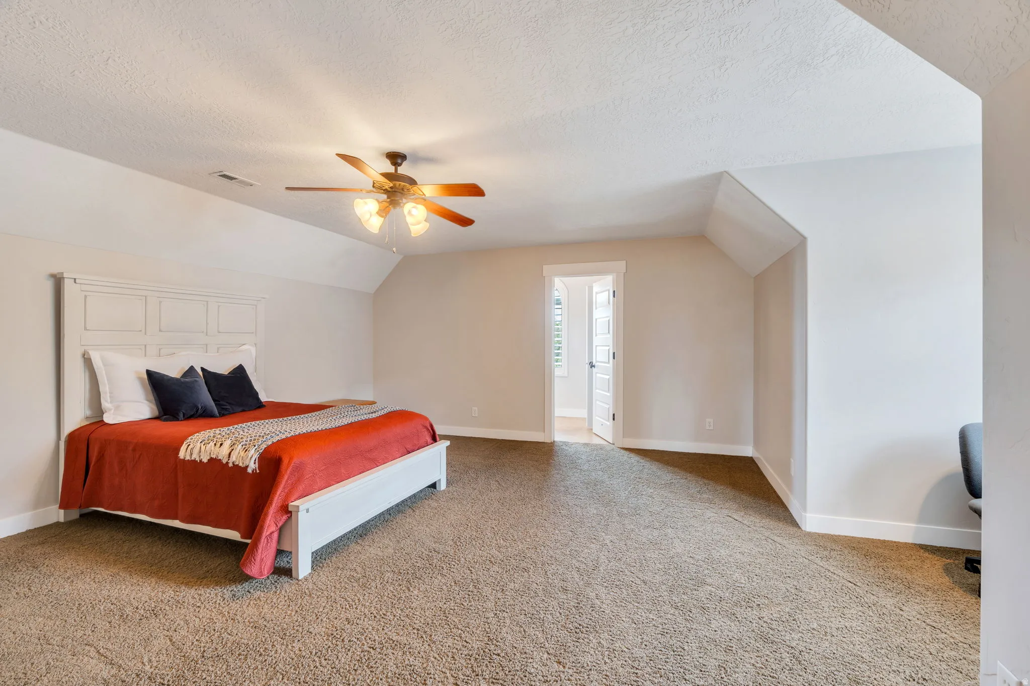 Carpeted bedroom featuring a ceiling fan, sloped ceilings, and white trim