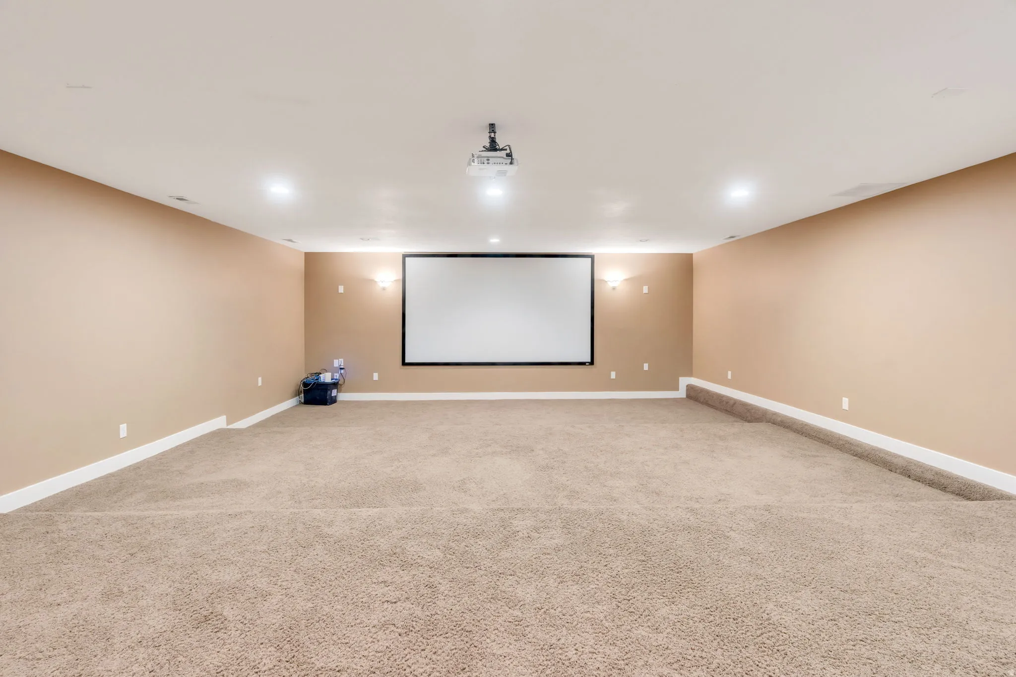 Dedicated home theater space featuring a large projection screen and ceiling-mounted projector