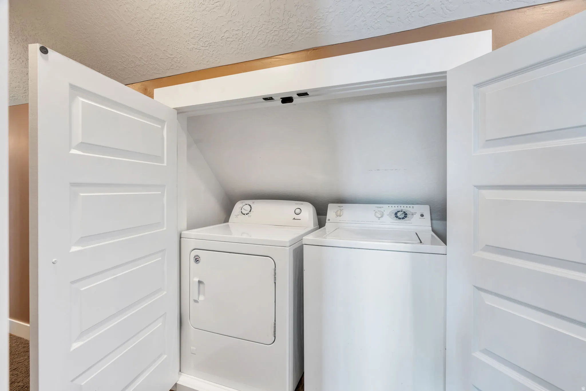 Laundry area featuring a textured ceiling and separate washer and dryer