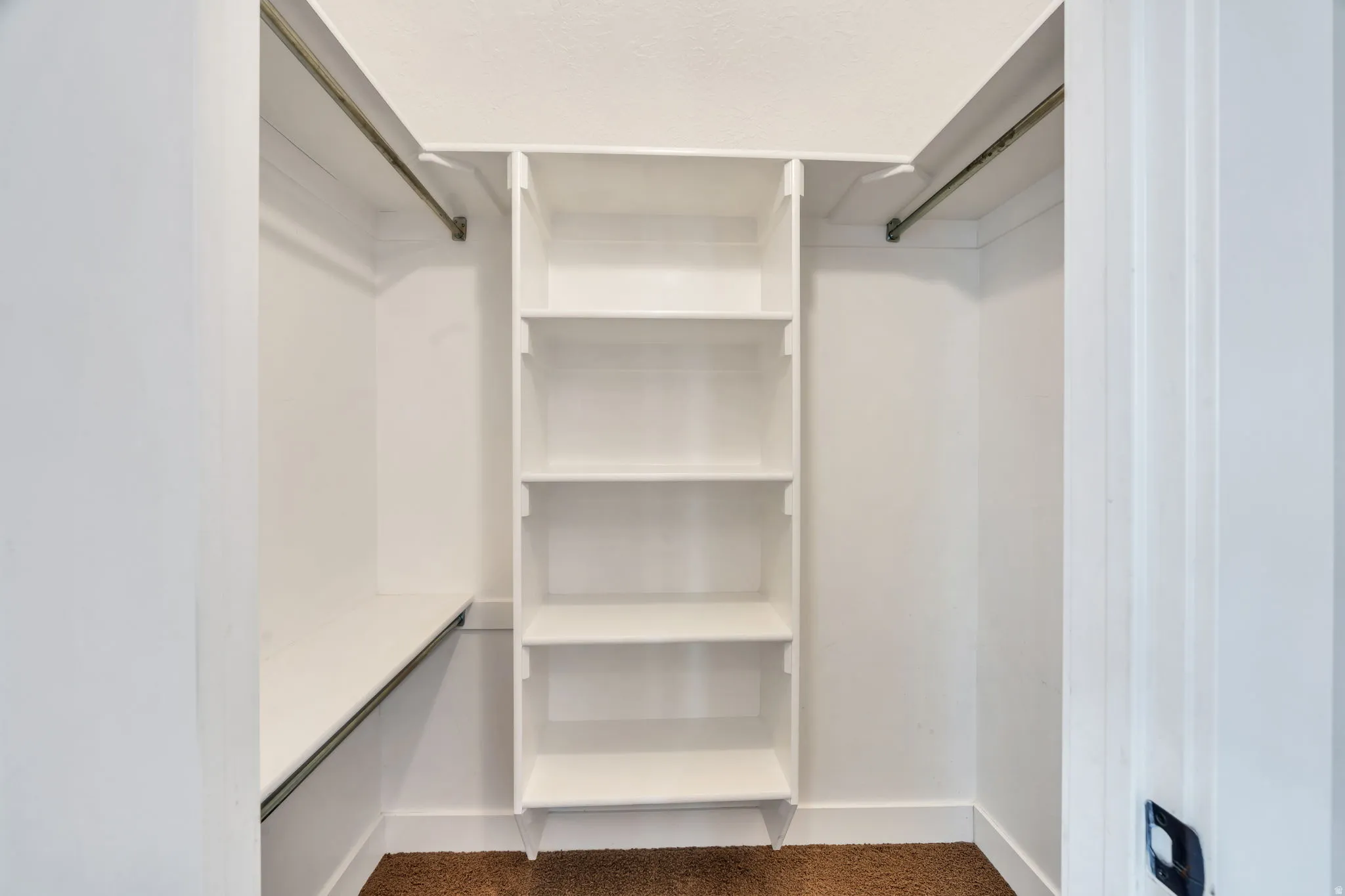 Walk-in closet featuring built-in shelving, two hanging rods, and a lower storage shelf