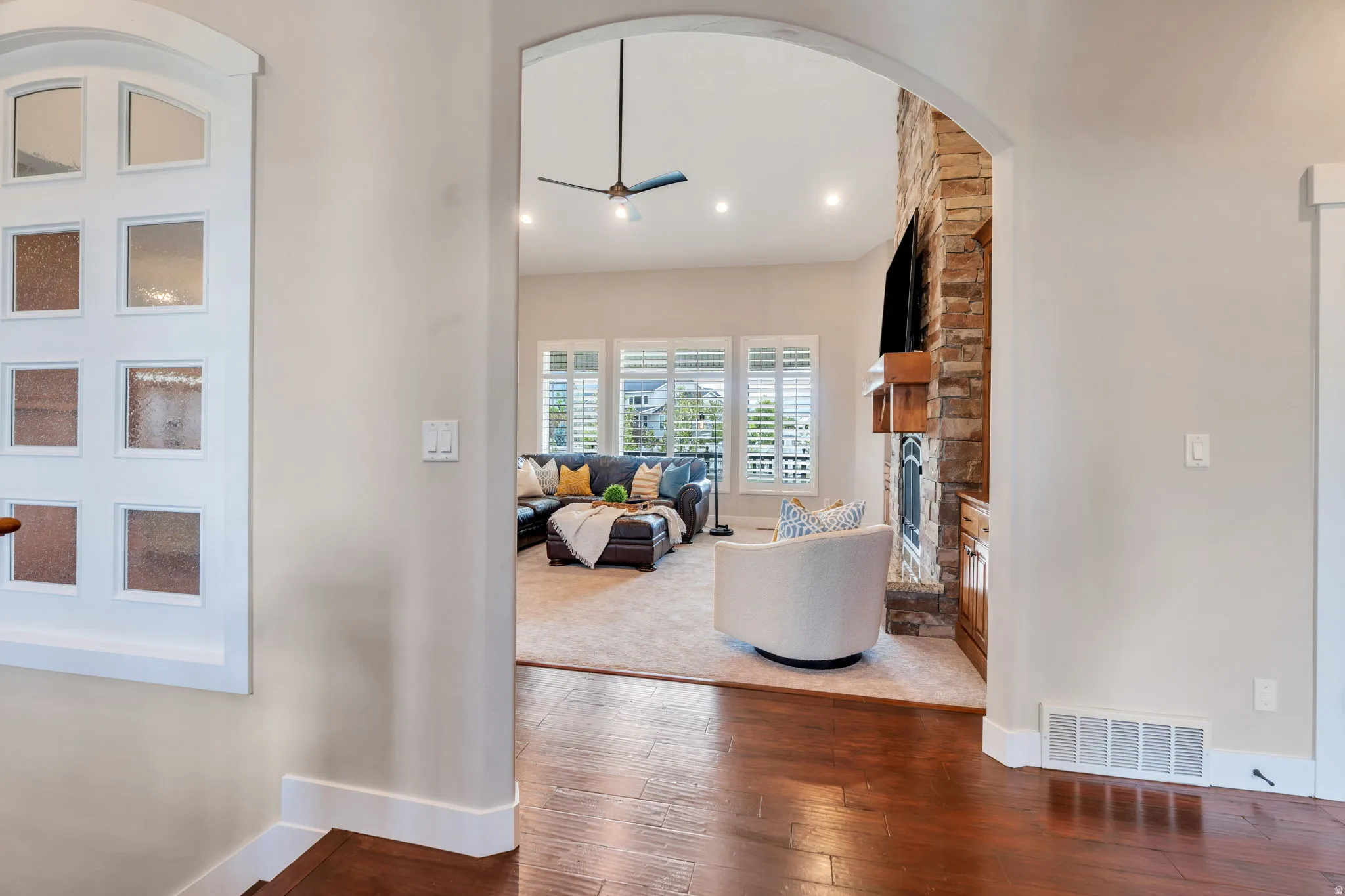 Living area with ceiling fan, hardwood / wood-style flooring, a fireplace, and arched walkways