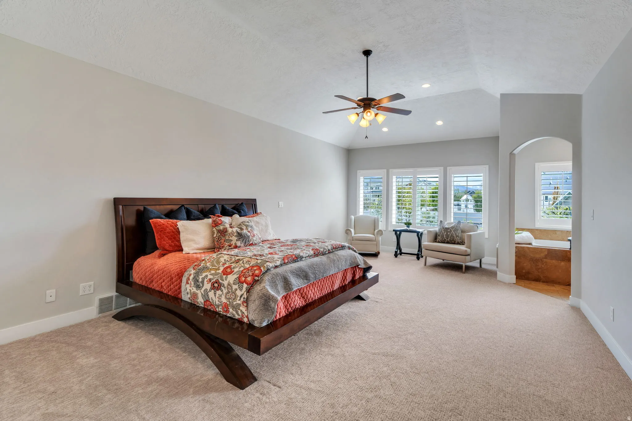 Bedroom with a ceiling fan, light colored carpet, and arched walkways