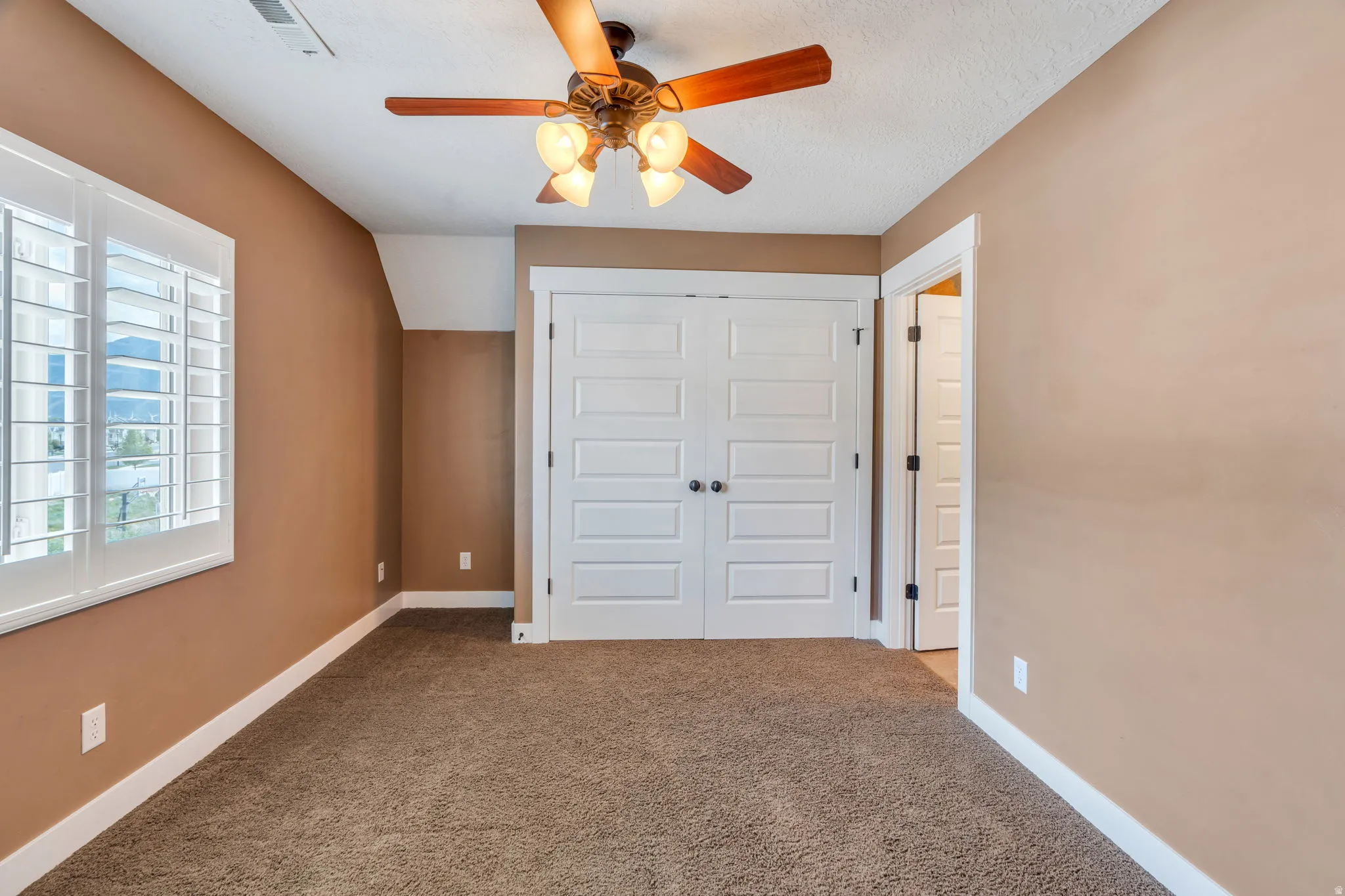 Unfurnished bedroom featuring a closet, carpet floors, ceiling fan, and vaulted ceiling