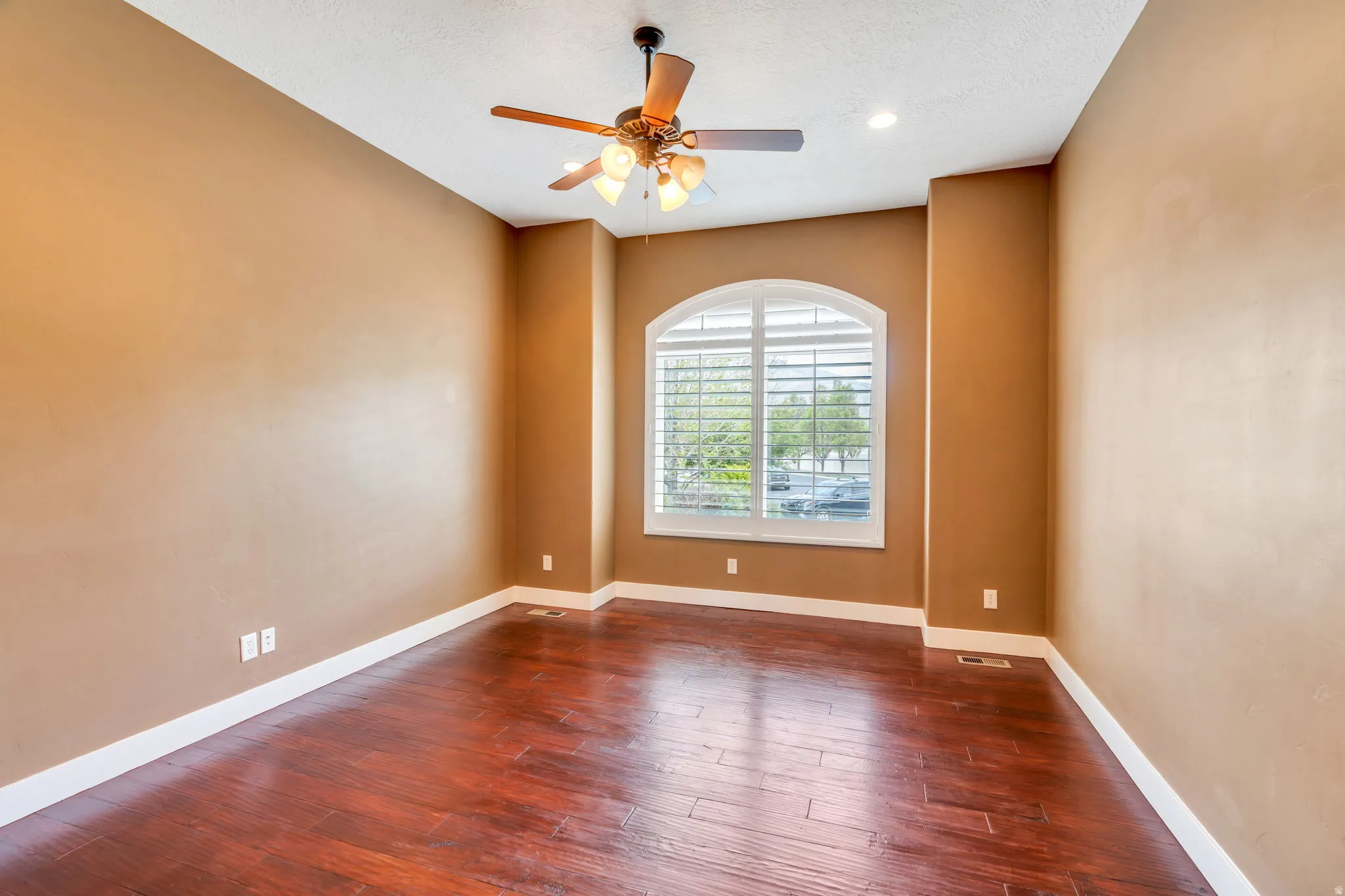 Spare room featuring dark wood-style floors, ceiling fan, and a textured ceiling