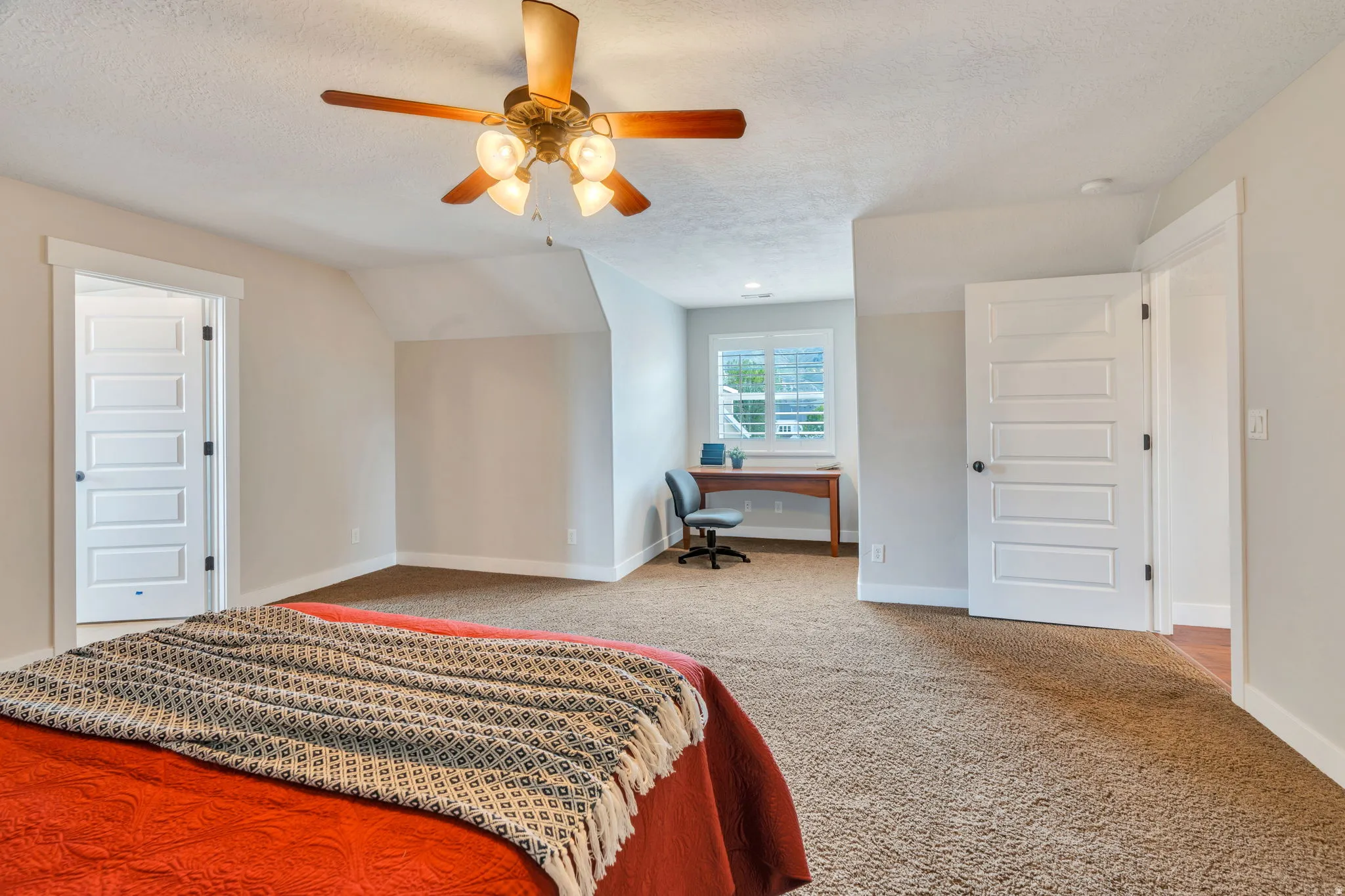 Bedroom with an office area, light carpet, and a ceiling fan