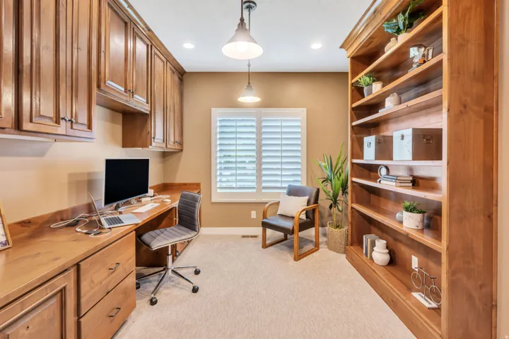 Dedicated workspace featuring extensive built-in cabinetry, a built-in desk with a wood-finish surface, and a full-height built-in bookcase