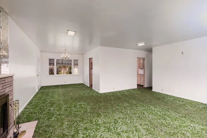 Spare room featuring suspended lighting, a glass covered fireplace, and carpet