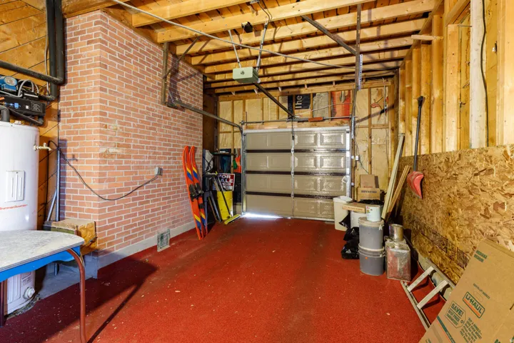 Garage featuring electric water heater and a garage door opener