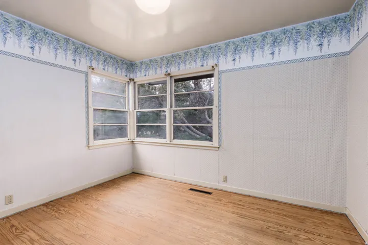 Spare room with light wood finished floors and wallpapered walls