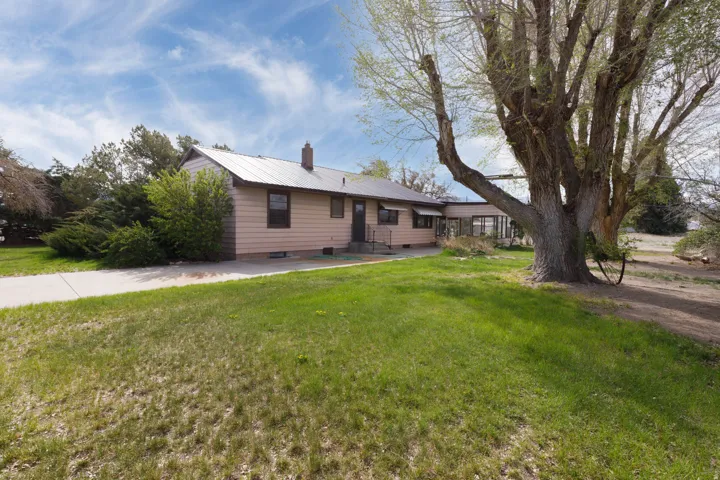 Single story home featuring a chimney, a patio area, a front yard, a metal roof, and crawl space