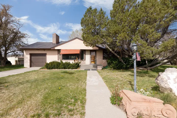 View of front of property with a front lawn, a chimney, an attached garage, and concrete driveway