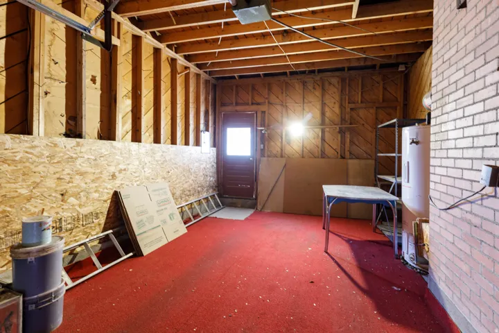 Miscellaneous room with electric water heater, brick wall, and carpet flooring