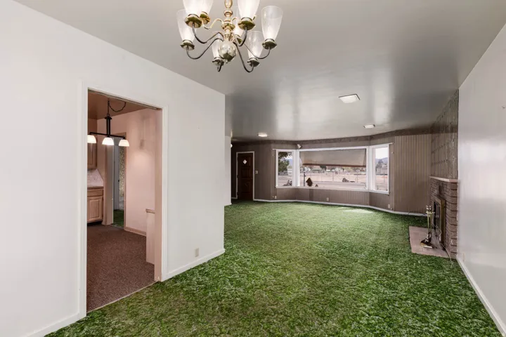 Carpeted empty room with baseboards and hanging lights