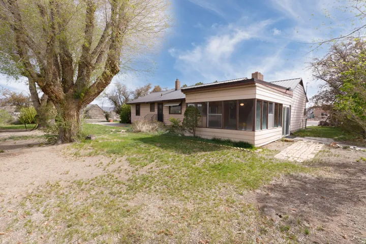 Back of house with a chimney, a sunroom, a lawn, and a metal roof