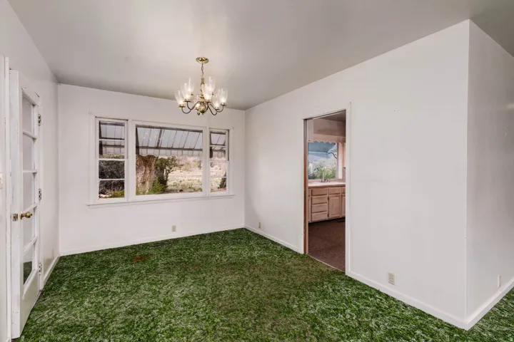 Unfurnished dining area featuring dark carpet and suspended lighting