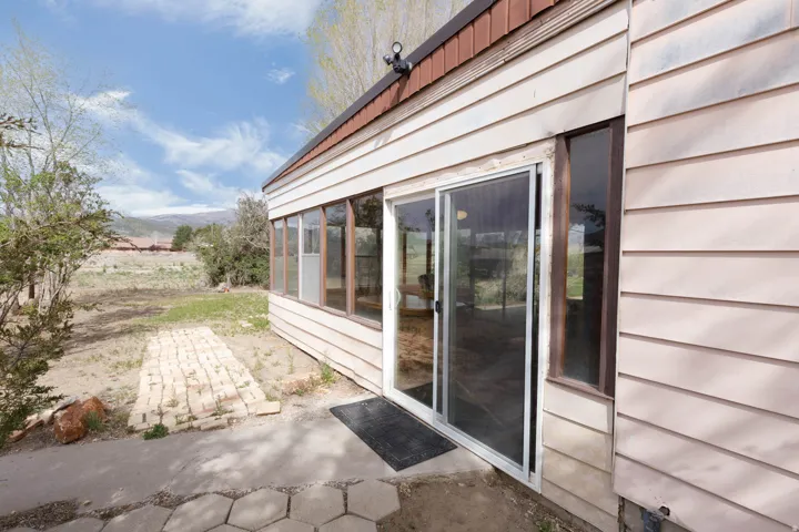 View of exterior entry with a sunroom, a mountain view, and a patio area