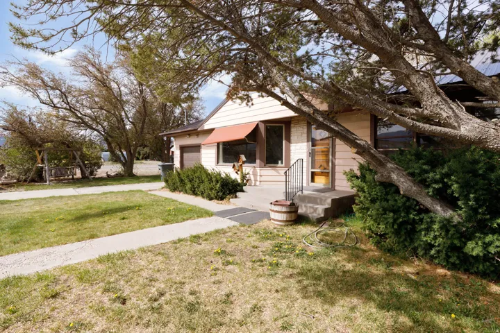 Bungalow featuring a front lawn, an attached garage, and driveway