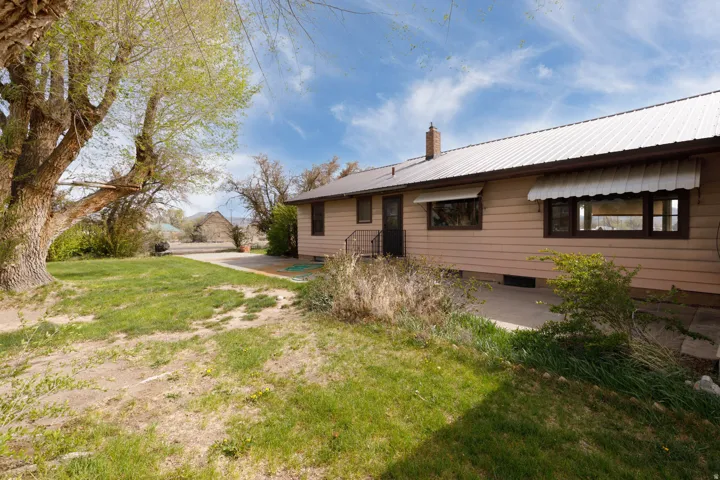 Back of house with a patio area, a lawn, a metal roof, and a chimney