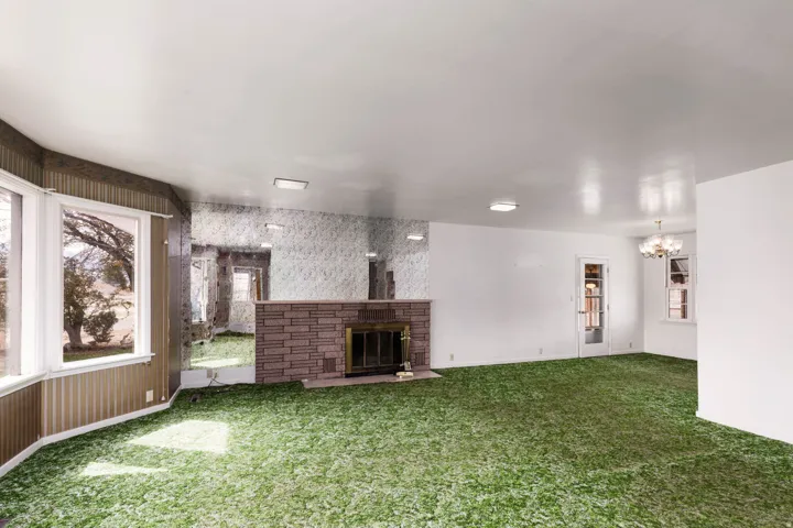 Unfurnished living room featuring healthy amount of natural light, carpet, wallpapered walls, a fireplace, and suspended lighting