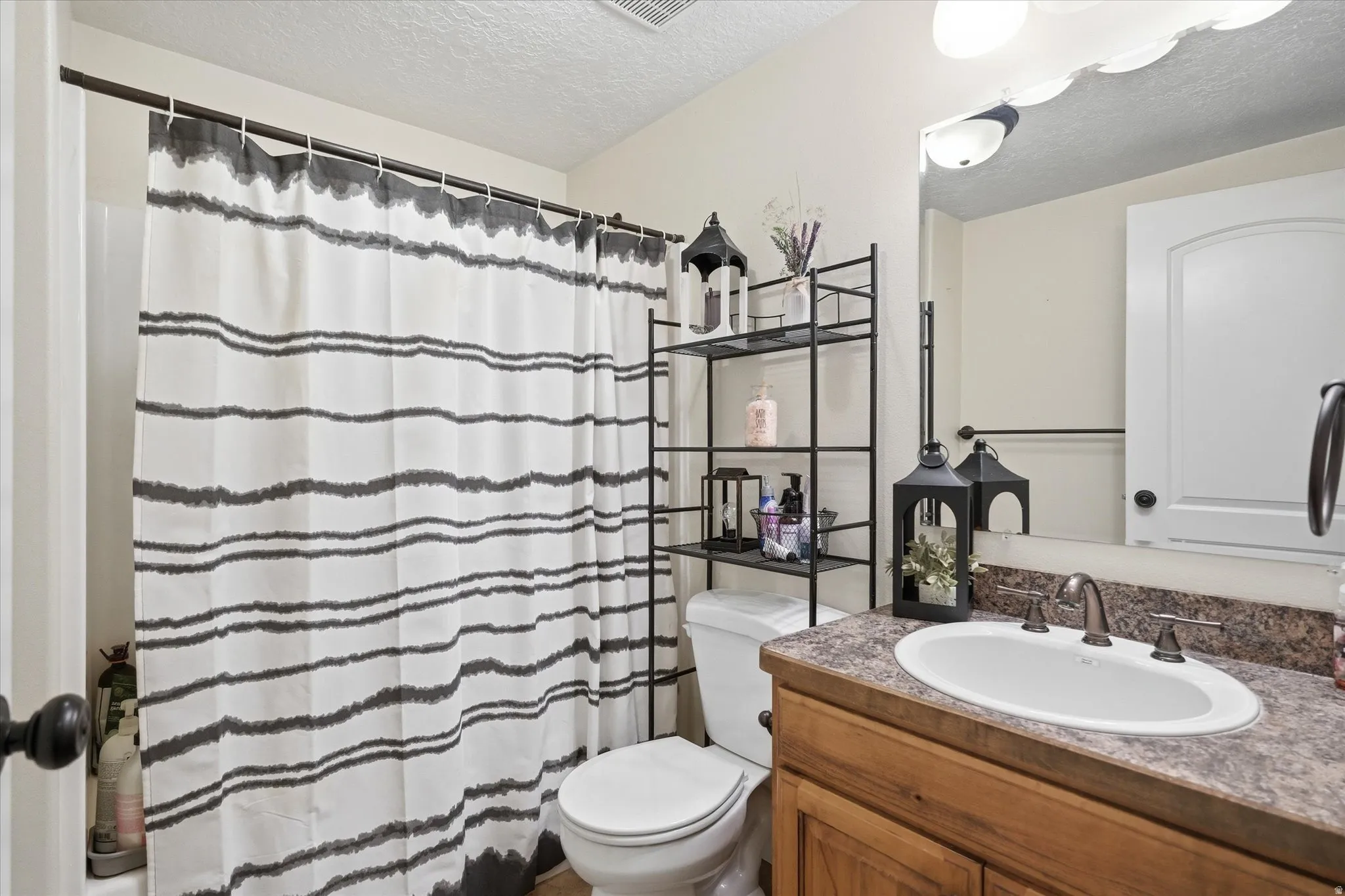 Full bath with a shower with curtain, vanity, and a textured ceiling