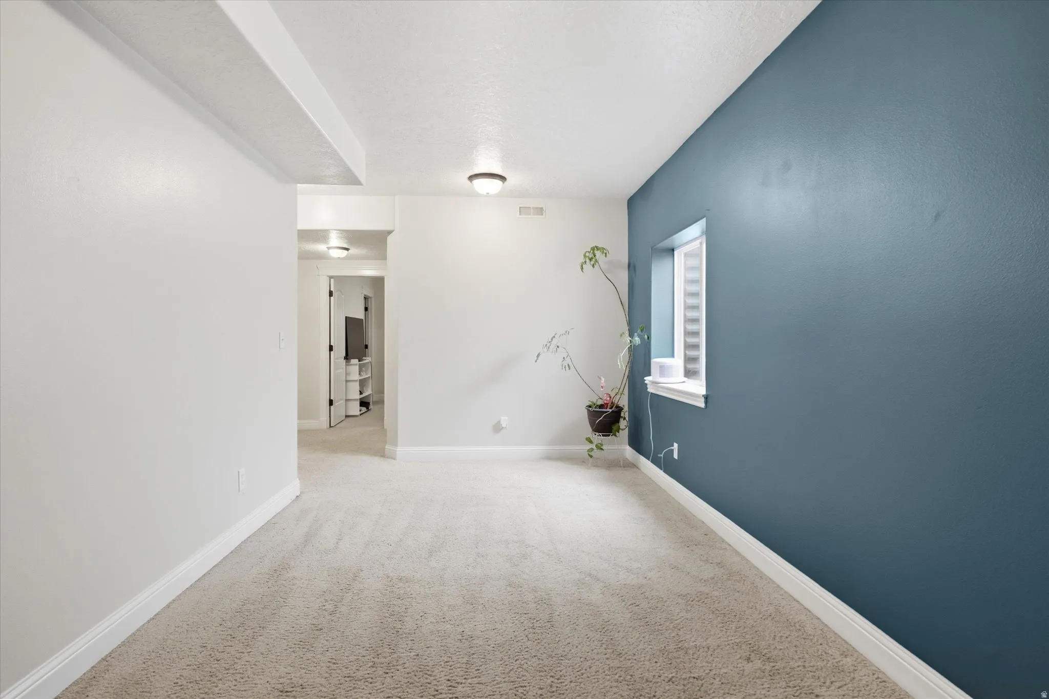 Unfurnished room with baseboards and light colored carpet