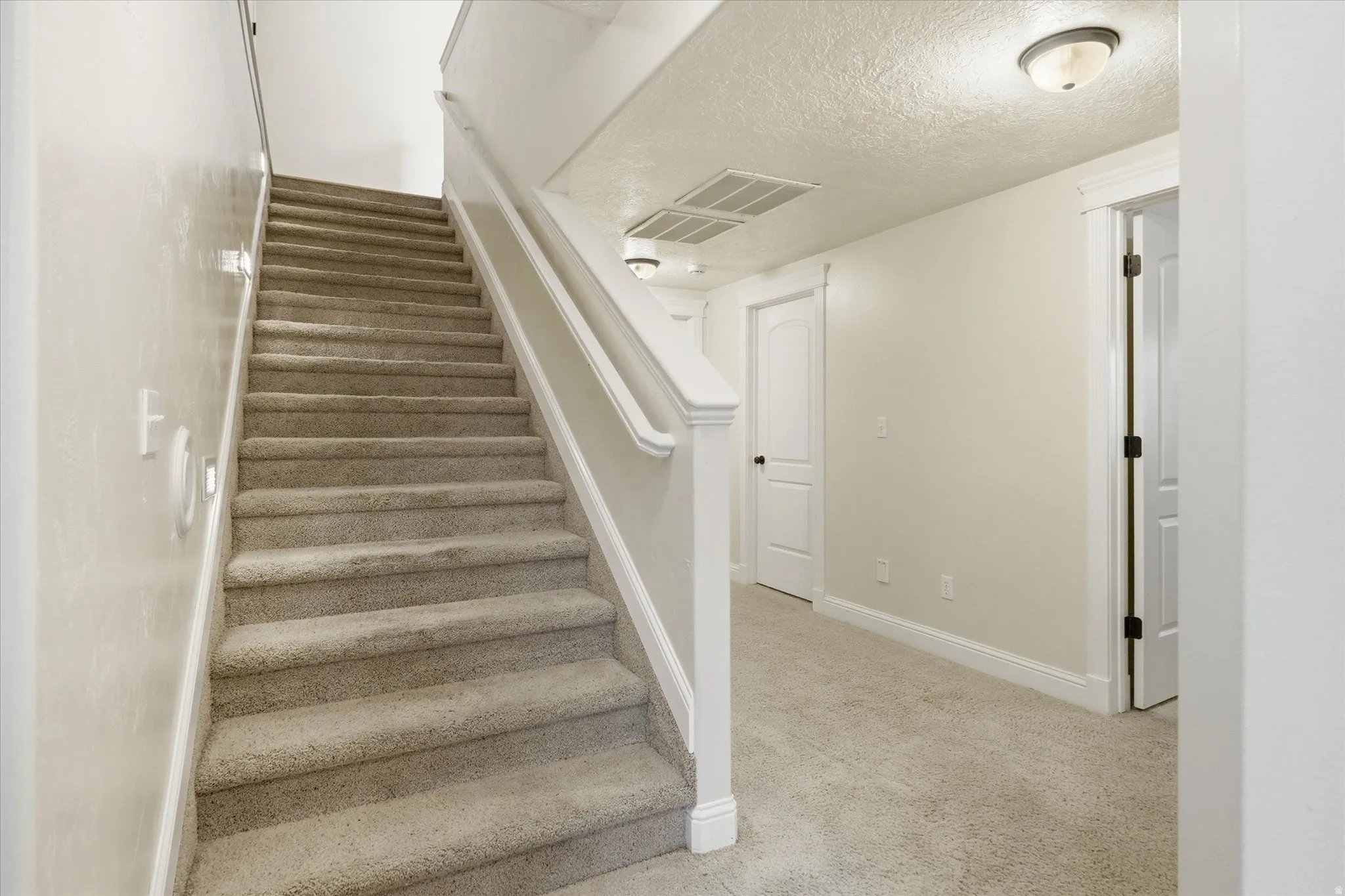 Stairway with a textured ceiling and carpet flooring