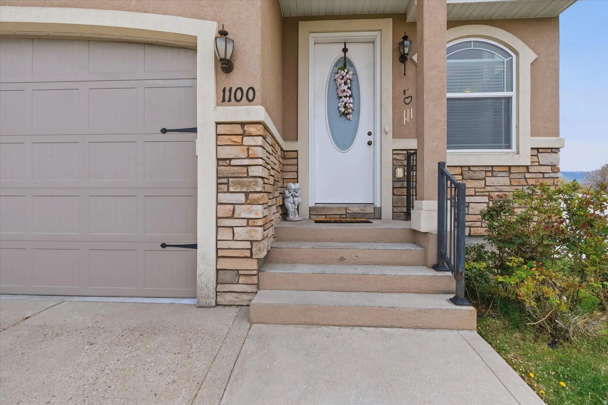 Entrance to property featuring stone siding, stucco siding, and a garage