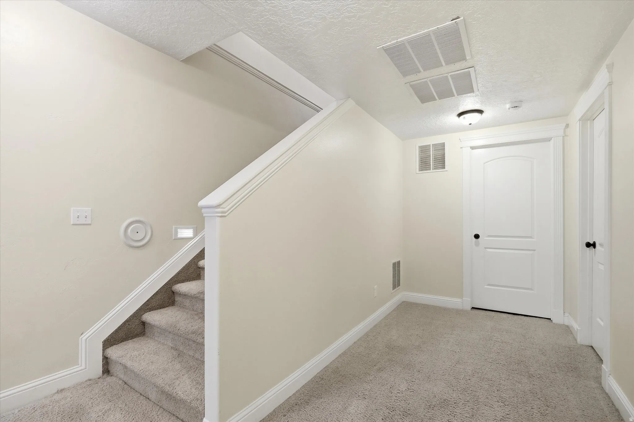 Stairway with a textured ceiling and carpet flooring