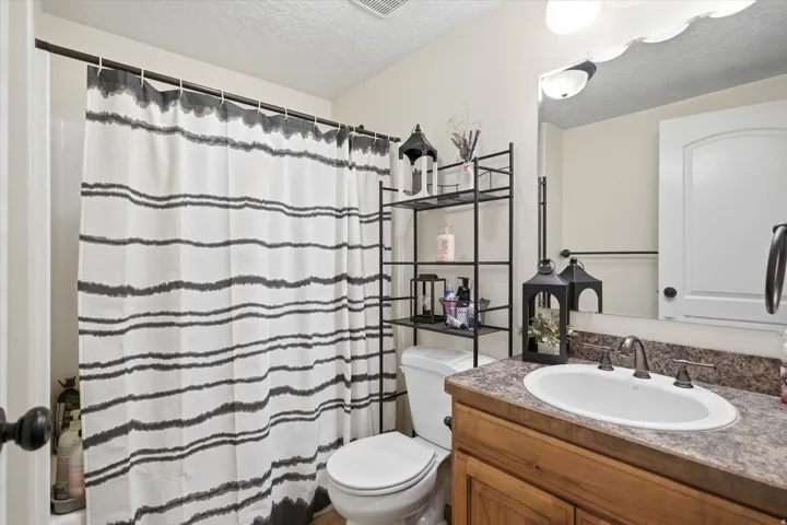 Full bath with a shower with curtain, vanity, and a textured ceiling