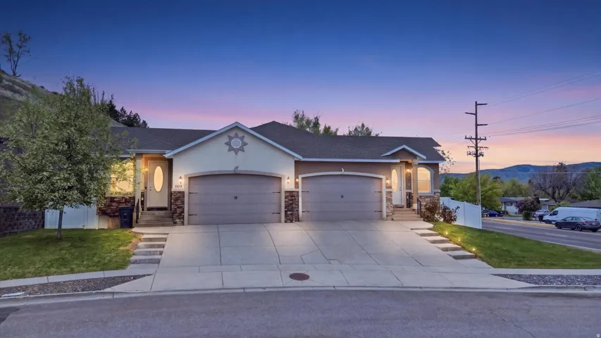 Ranch-style home with a garage, stucco siding, stone siding, and a front yard