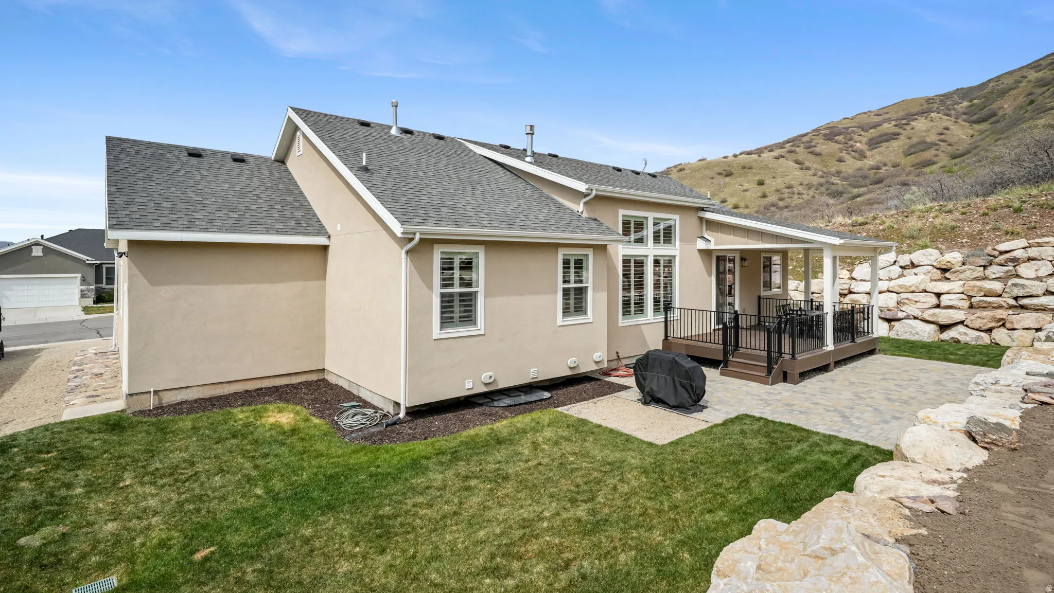 Rear view of house featuring roof with shingles, a patio, stucco siding, a yard, and a covered deck