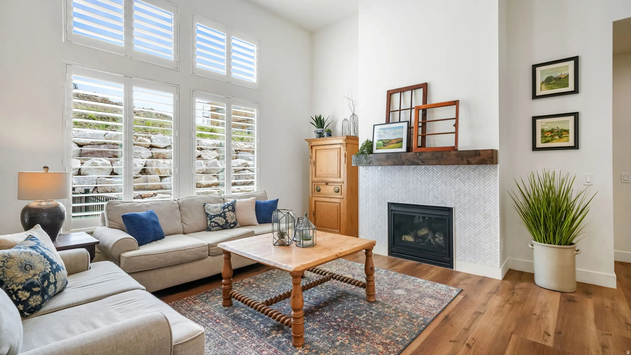 Living area with a high ceiling, lots of natural light, and a tiled fireplace