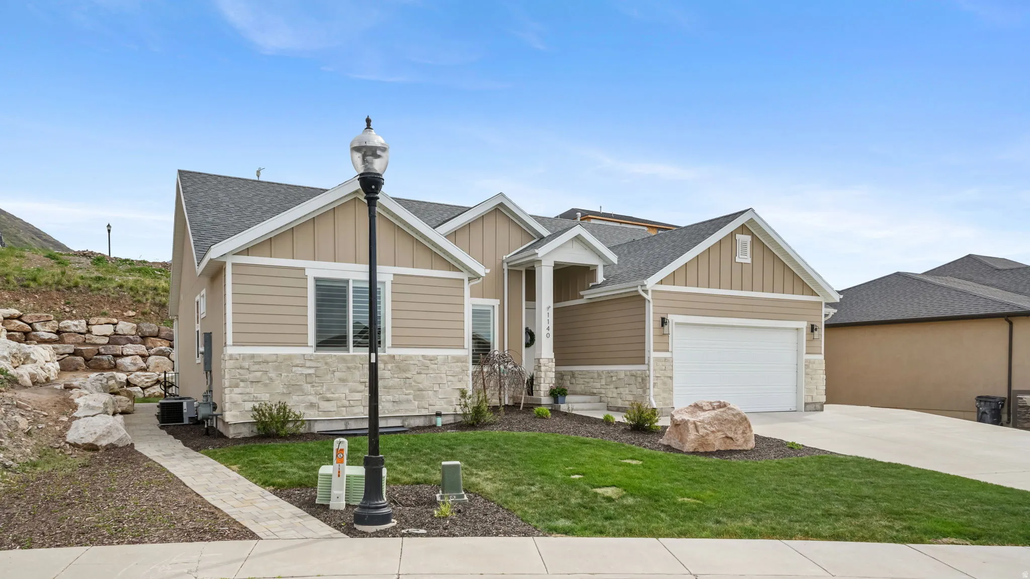 Craftsman-style home with board and batten siding, stone siding, an attached garage, and concrete driveway