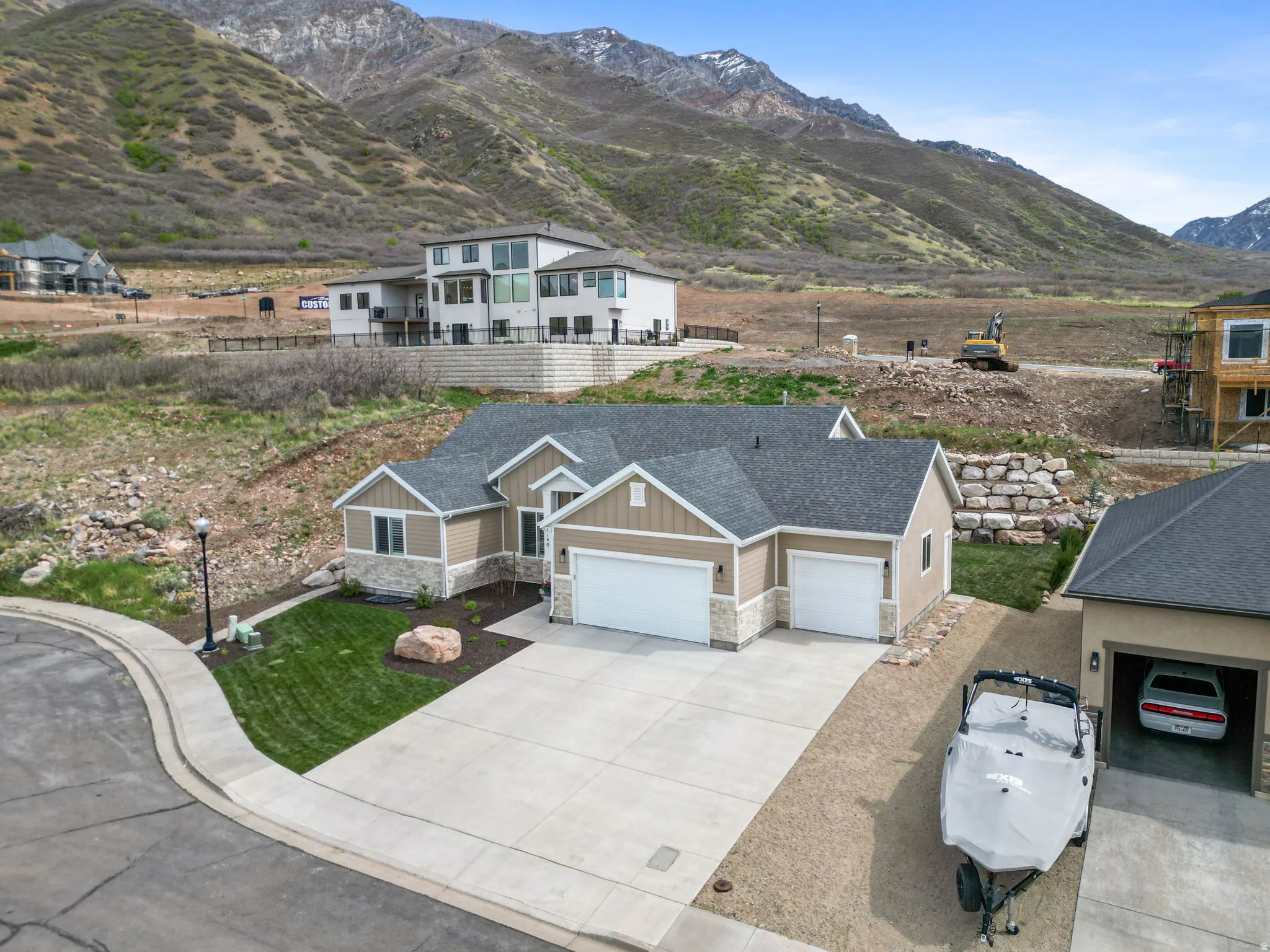 View of front facade with stone siding, board and batten siding, an attached garage, a mountain view, and concrete driveway