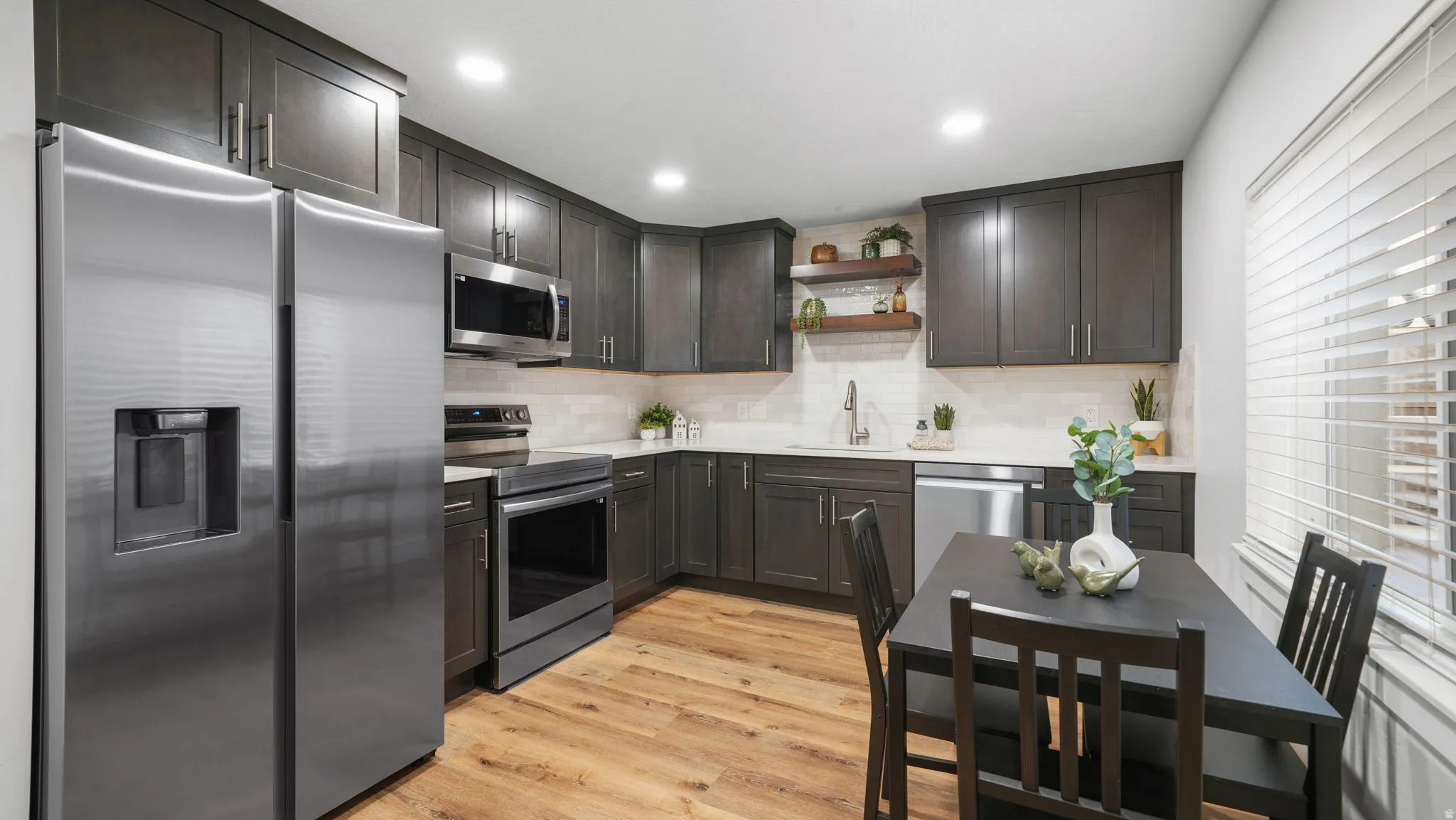 ADU Kitchen with stainless steel appliances, light wood-type LVP flooring, open shelves, dark wood finish cabinets, and decorative backsplash
