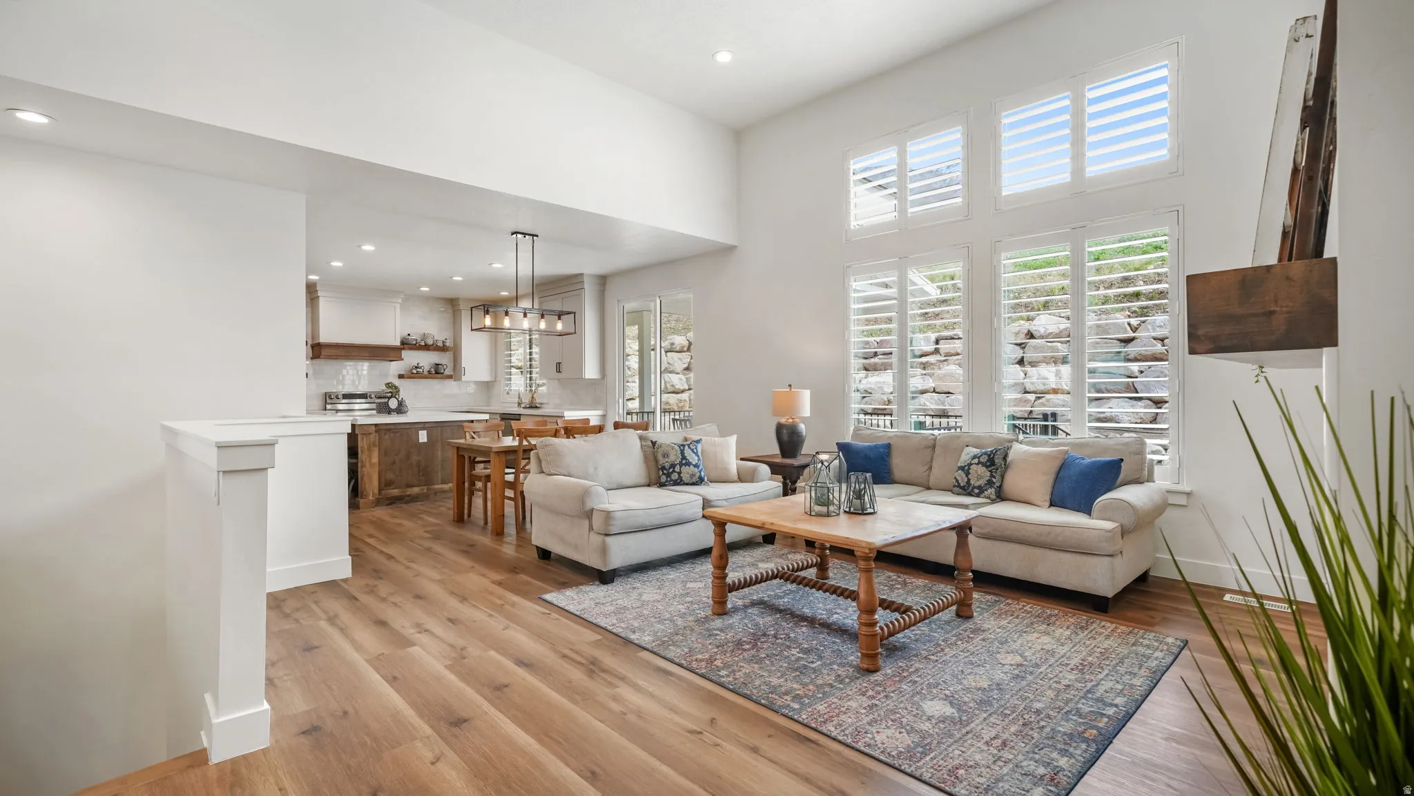 Open concept living area with wood-type LVP floors, a high ceiling, and recessed lighting