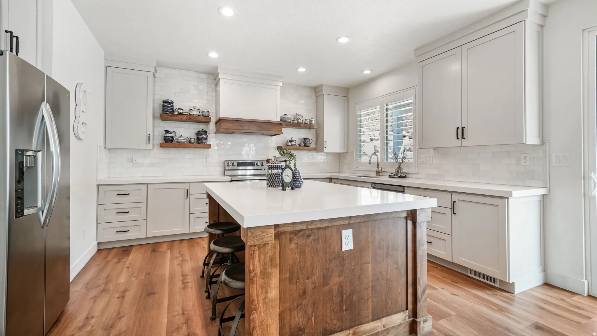 Kitchen featuring quartz counters, light cabinets, island seating, tile backsplash