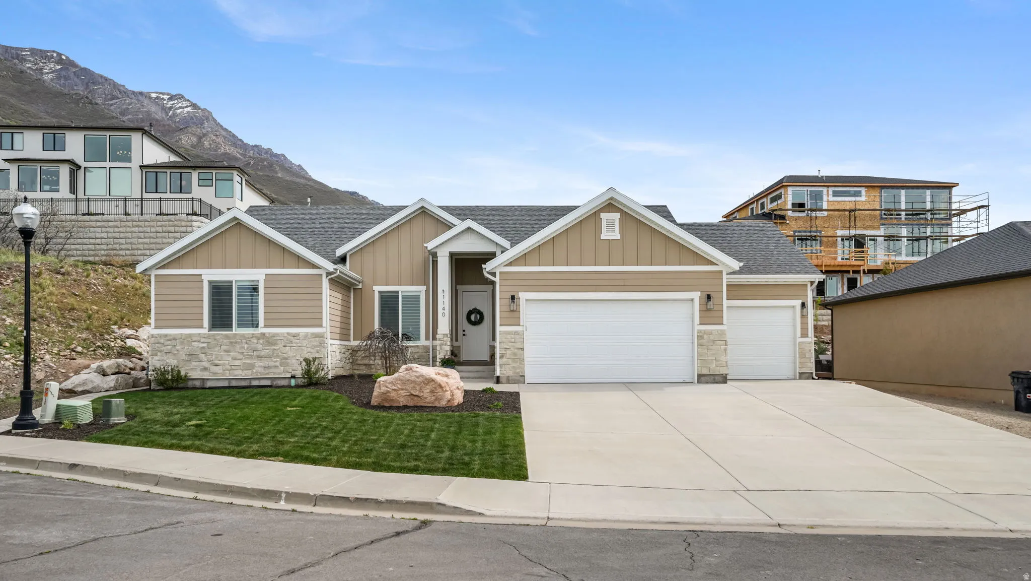 Craftsman-style home featuring stone siding, board and batten siding, a 3-car garage, and driveway