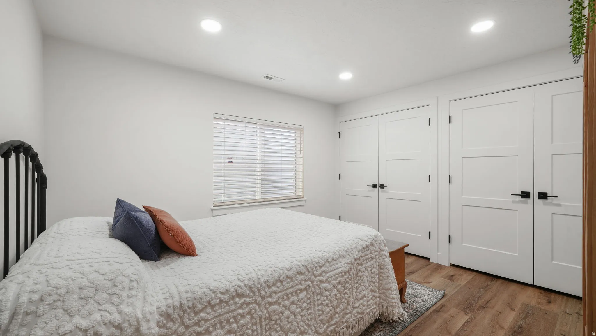 Bedroom 4 featuring light wood-style LVP floors, recessed lighting, and two closets (one has laundry hookups.)