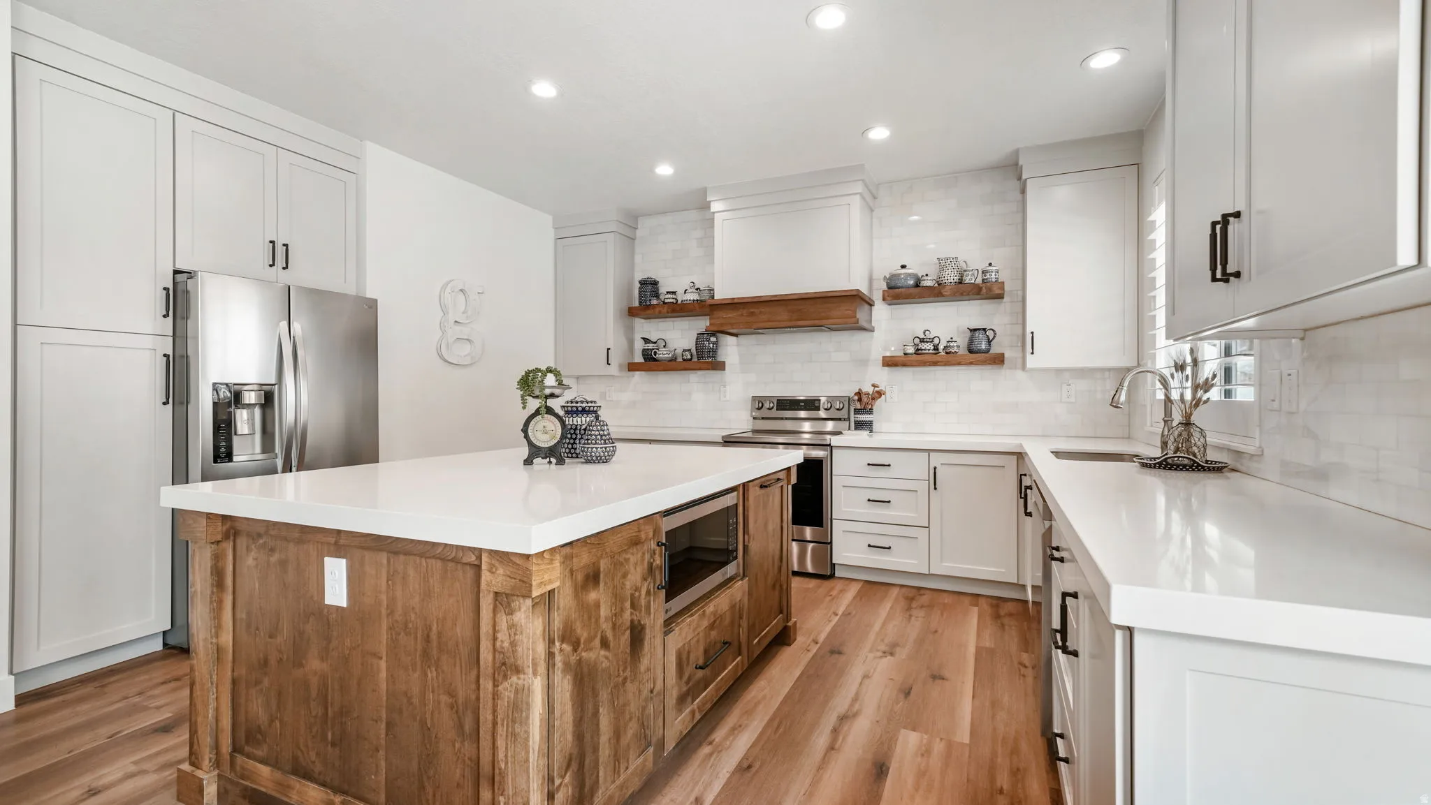 Dual tone kitchen with dual tone cabinetry, open shelves, a kitchen island, stainless steel appliances, and light wood-type LVP flooring