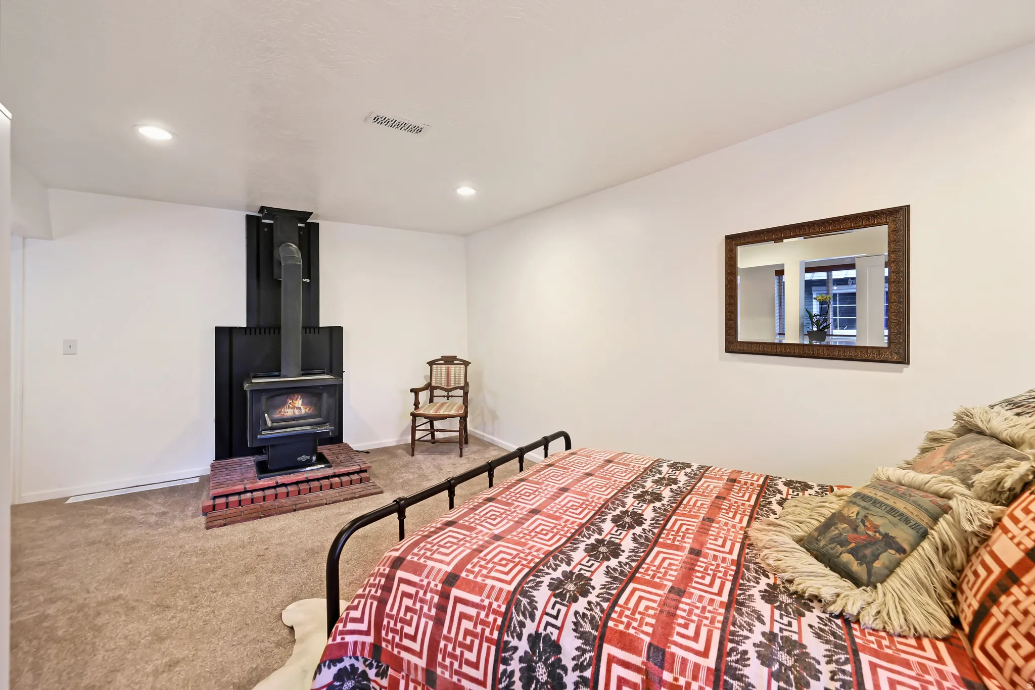 Bedroom featuring carpet floors, recessed lighting, and a wood stove