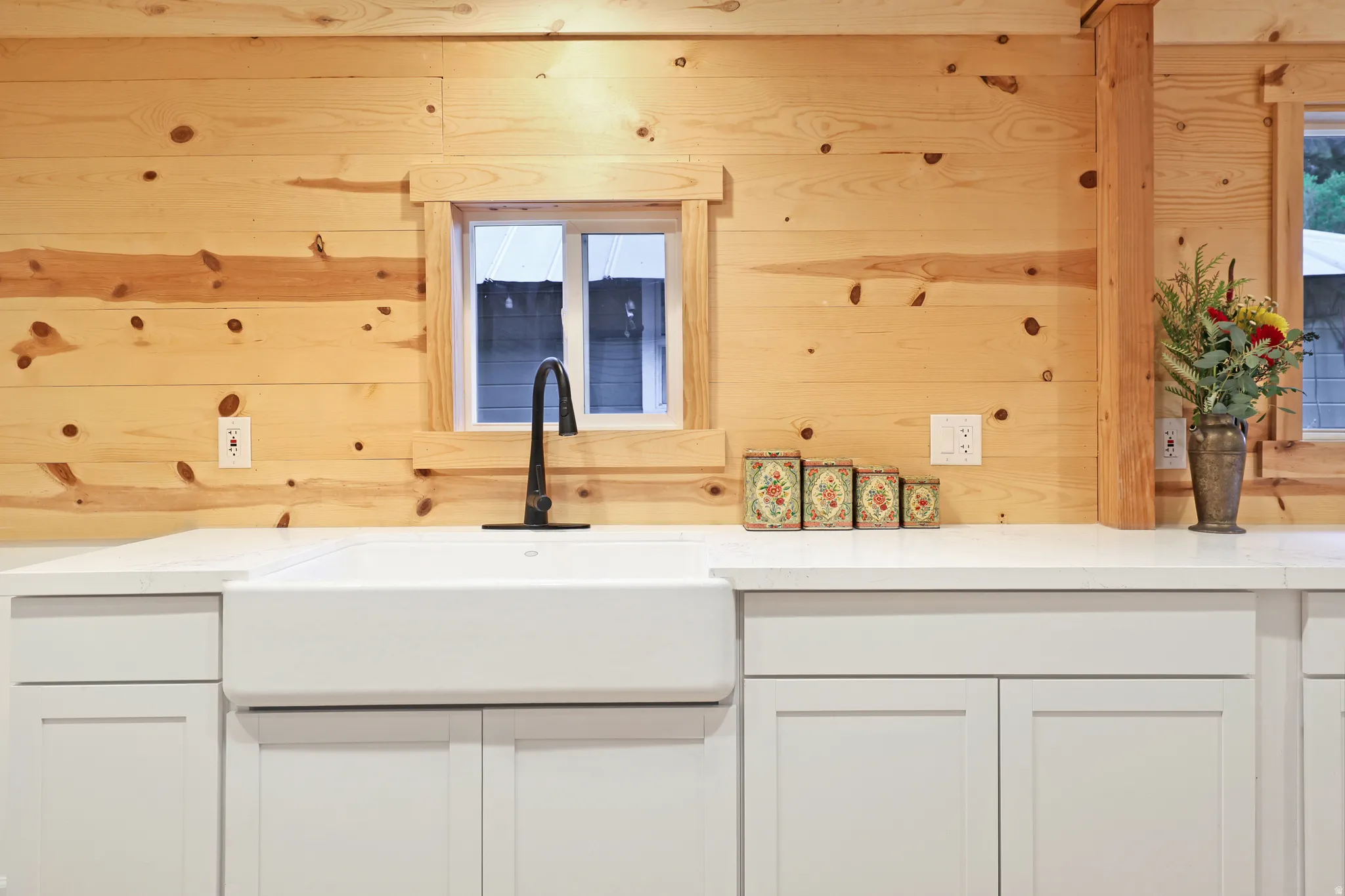 Kitchen featuring white cabinets, wood walls, and light stone counters