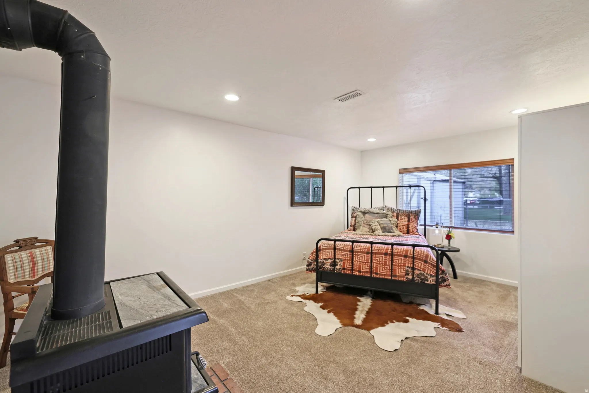 Bedroom featuring a wood stove, light colored carpet, and recessed lighting