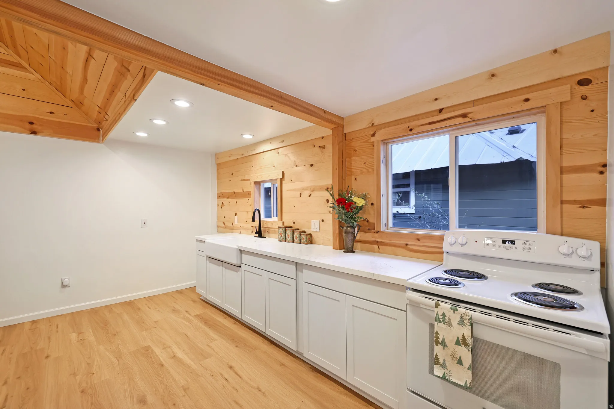 Kitchen featuring electric range, wooden walls, light wood-type flooring, recessed lighting, and white cabinetry