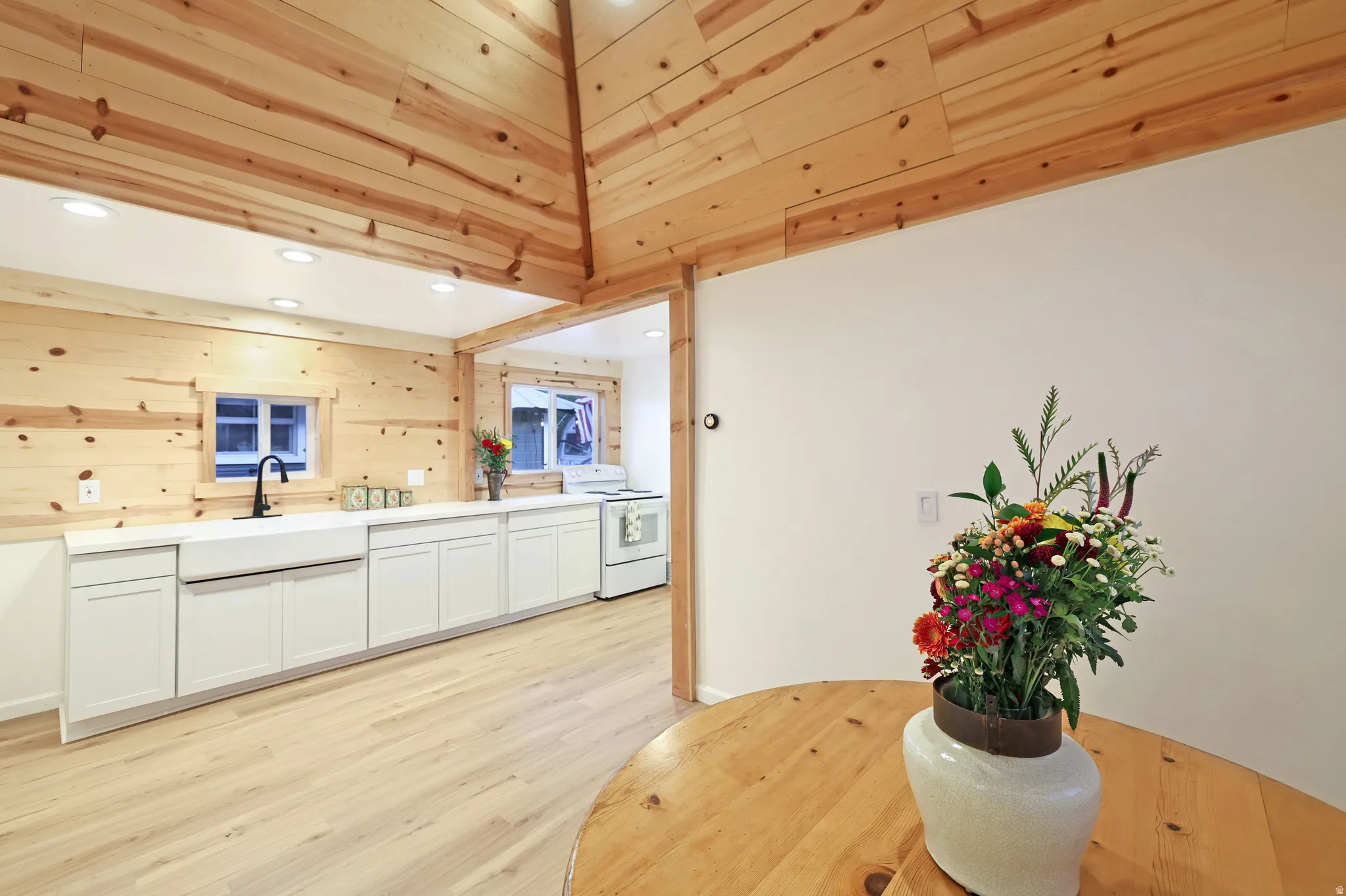 Kitchen with white cabinetry, light wood finished floors, white electric range oven, recessed lighting, and wooden walls