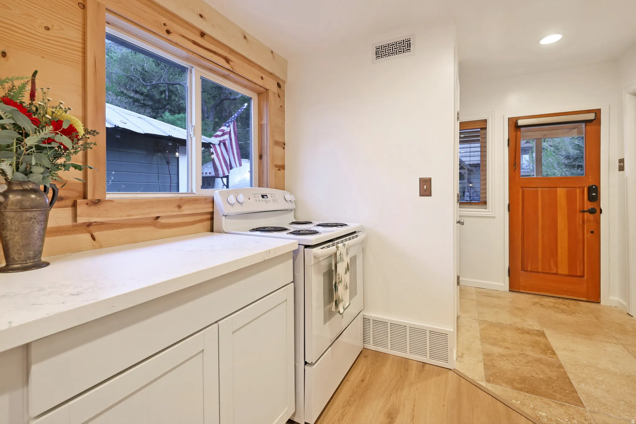 Kitchen featuring white range with electric cooktop, white cabinetry, light wood-style flooring, and light stone counters