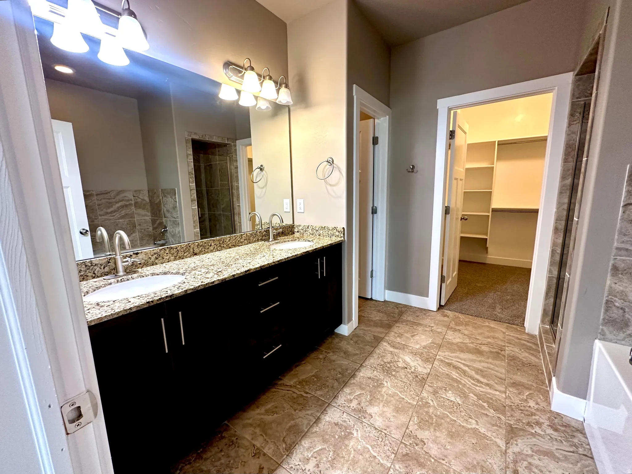 Bathroom with double vanity, a walk in closet, a stall shower, and a tub