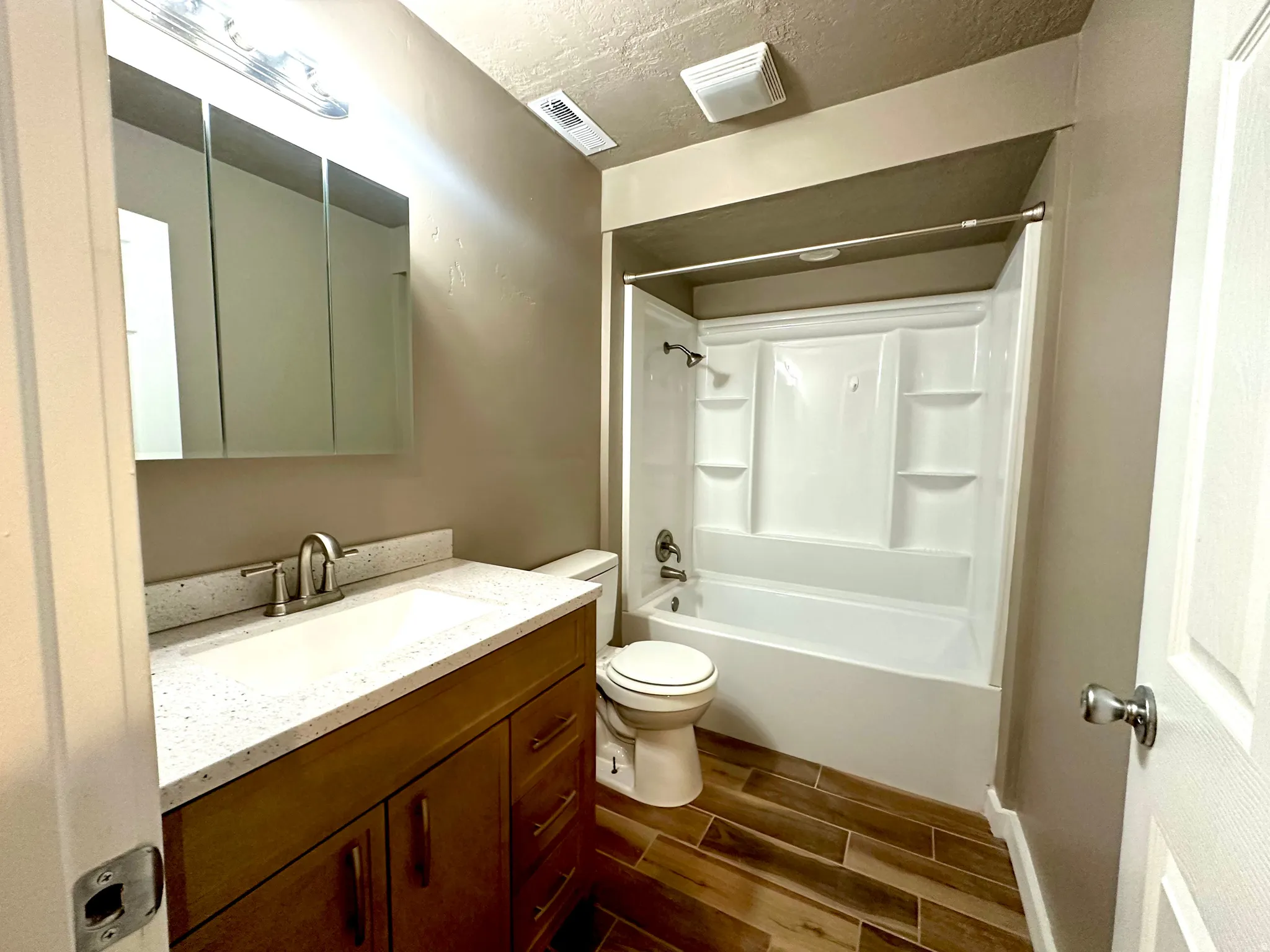 Basement Bathroom featuring wood tiled floors, vanity, bathtub / shower combination, and a textured ceiling